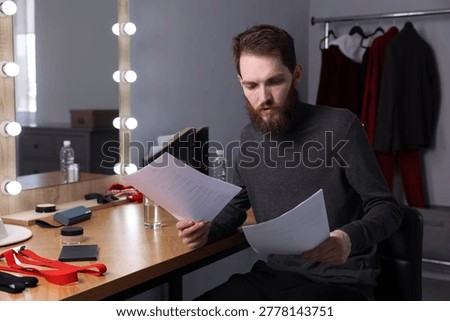 Actor with script rehearsing his lines in dressing room