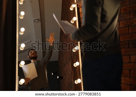 Actor with script rehearsing his lines near mirror in dressing room