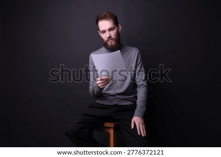 Actor with script rehearsing on black background