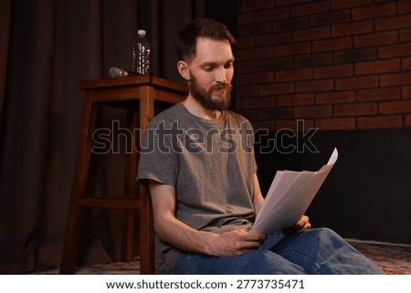 Actor with script rehearsing on floor indoors