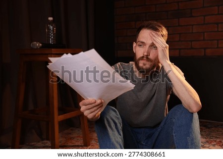 Actor with script rehearsing on floor indoors