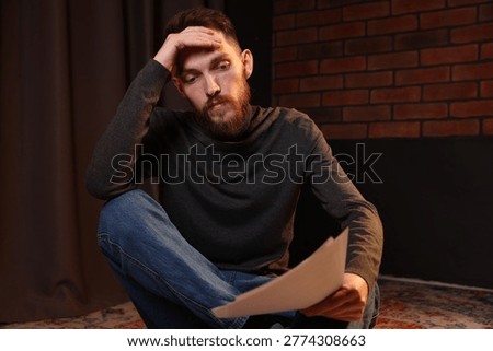 Actor with script rehearsing on floor indoors