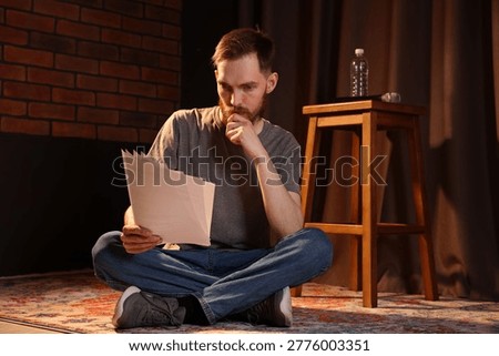 Actor with script rehearsing on floor indoors