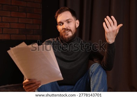 Actor with script rehearsing on floor indoors