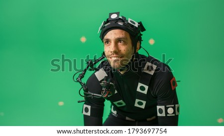 Actor Wearing Motion Caption Suit and Head Rig acts as an Animal or a Monster for CGI Green Screen Scene. Filmmaking On Film Studio Set Shooting Blockbuster Movie with Chroma Key.
