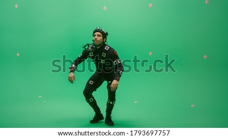 Actor Wearing Motion Caption Suit and Head Rig acts as an Animal or a Monster for CGI Green Screen Scene. Big Budget Filmmaking On Film Studio Set Shooting Blockbuster Movie with Chroma Key