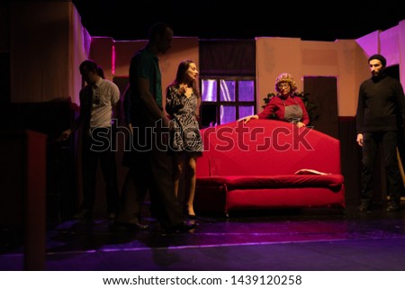 Actors and actresses play comedic roles in a show performance on a theater stage.