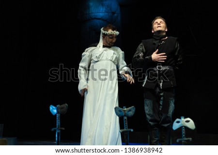 Actors in black suit and white female dress on the stage of the theater show performance.