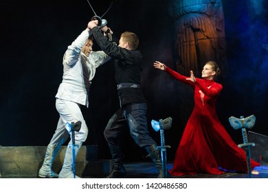 Actors In Black And White Clothes With Woman In Red Dress Play A Duel With Swords Performance On The Theater Stage