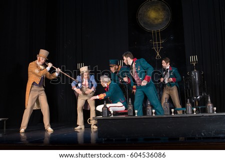 Actors of men in antique clothes, frock coats and uniforms posing on stage in the background of scenery