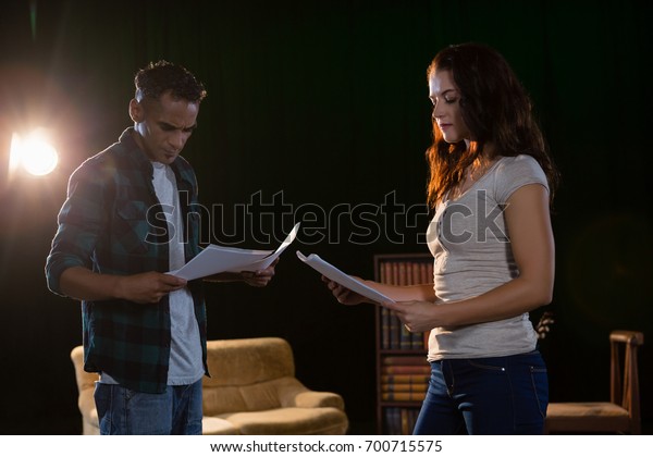 Actors reading\
their scripts on stage in\
theatre