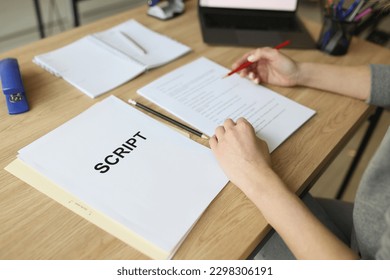 Actress checks script papers for filming movie making notes with pencil. Woman edits text at wooden table in office and prepares for playing role