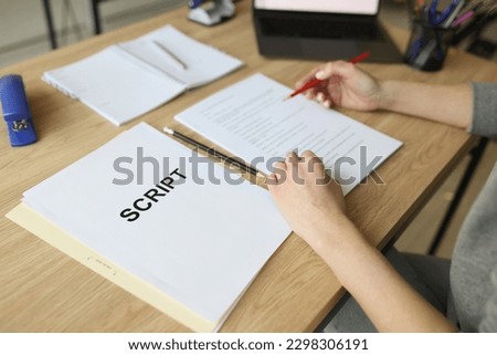 Actress checks script papers for filming movie making notes with pencil. Woman edits text at wooden table in office and prepares for playing role