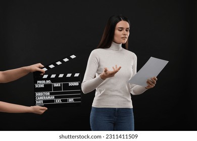 Actress performing while second assistant camera holding clapperboard on black background. Film industry