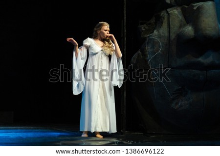 Actress in white costume plays a drama performance on the stage of the theater
