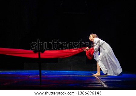 Actress in white costume plays a drama performance on the stage of the theater
