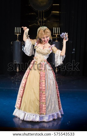 actress woman in a medieval dress with a puffed skirt is posing against the backdrop of the scenery for the play