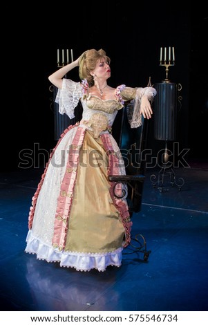 actress woman in a medieval dress with a puffed skirt is posing against the backdrop of the scenery for the play