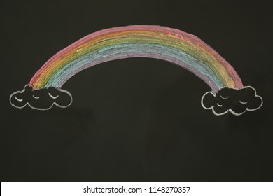 Actual drawing on black chalk board. Colorful rainbow on clouds.