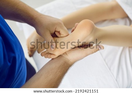 Acupressure therapy and reflexology specialist affecting special points and areas on young girl's feet. Qualified therapist doing remedial therapeutic stress reducing foot massage to female patient