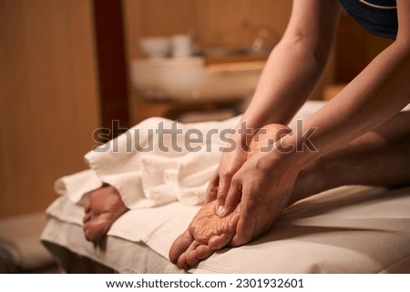 Acupressurist hands applying pressure to acupoint on man foot