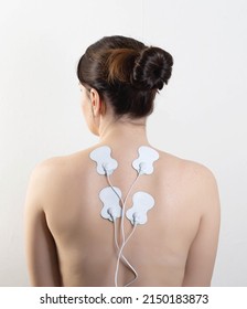 Acupuncture electronic massager on the back of a girl to relax muscles and relieve back pain