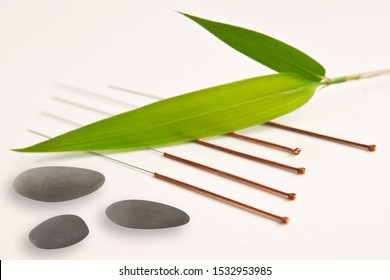 Acupuncture needles with bamboo leaf and stones background