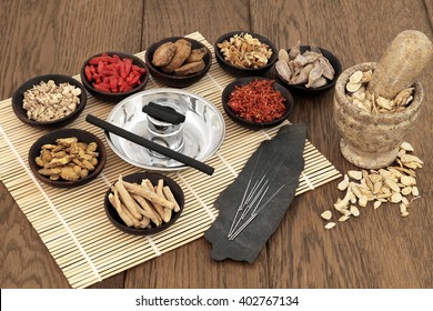 Acupuncture Needles, Moxa Sticks, Traditional Chinese Herbs For Herbal Medicine And Mortar With Pestle Over Bamboo And Old Oak Background.