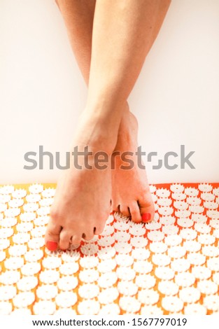 Acupuncture, stimulation of the soles of the feet. A girl is standing on a massage mat. Massage and healthy lifestyle.