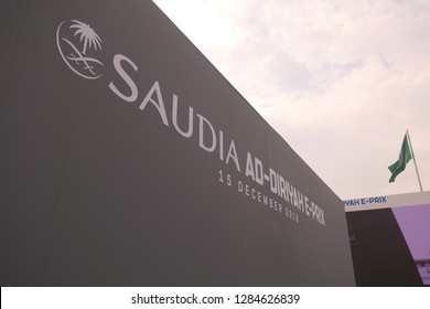 AD DIRIYAH, SAUDI ARABIA – DECEMBER 15, 2018: The Logo Of The SAUDIA Ad Diriyah FIA Formula E E-Prix Race With The Flag Of Saudi Arabia In The Background