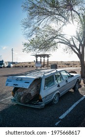 Adamana, Arizona, USA - April 10 2021: Vintage Station Wagon Car Weighed Down With Flat Tires Due To Trying To Haul And Steal A Giant Log Of Petrified Wood From Petrified Forest National Park.