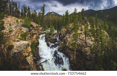 Adams Falls on a cloudy day with mountains and trees in the background along the East Inlet Trail of Rocky Mountain National Park, Colorado