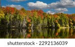 Adams reservoir in Woodford state park is surrounded by trees showing brilliant fall colors, near Woodford, Vermont