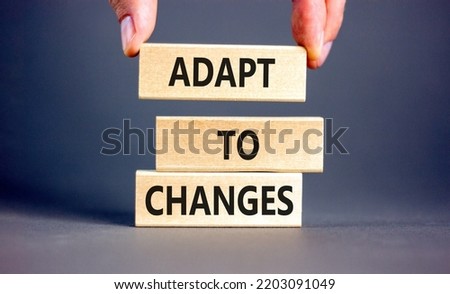 Adapt to changes symbol. Concept words Adapt to changes on wooden blocks. Businessman hand. Beautiful grey table grey background. Business and Adapt to changes quote concept. Copy space.