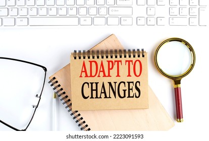 ADAPT TO CHANGES Text In Office Notebook With Keyboard, Magnifier And Glasses , Business Concept