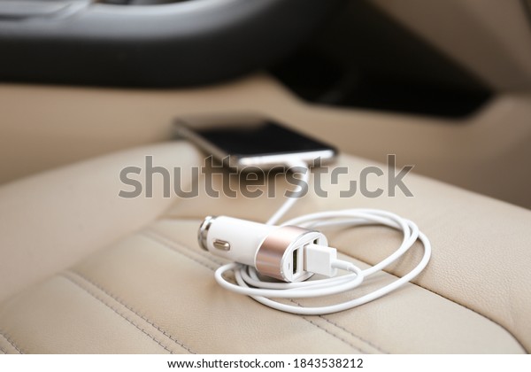 Adapter with connected charging cable and mobile\
phone in car, closeup