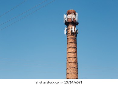 Adaptive Reuse Of An Old Industrial Building. Abandoned Factory Brick Tower With New, Modern Telecommunication Antennas. 