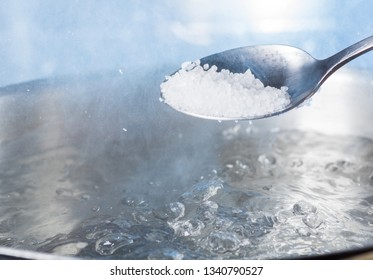 Add Salt To Boiling Water In A Metal Pan Close-up