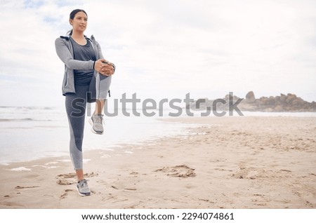 Add some variation to your workout sessions by heading to the beach. Shot of a sporty young woman stretching her legs while exercising on the beach.
