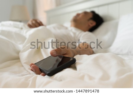 Addict man sleeping on home holding mobile phone in his hand in. Social media overuse ddiction and obsession concept.