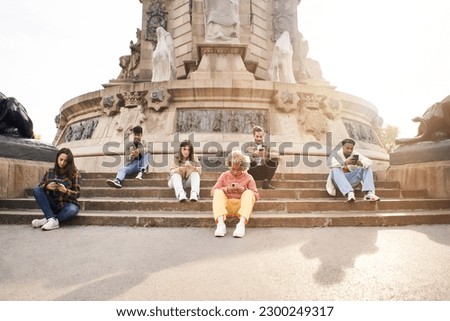 Addicted group of friends using their smart phones. Individualistic people focused on their mobiles sitting on a staircase in a city. Technology and individualism concept. High quality photo