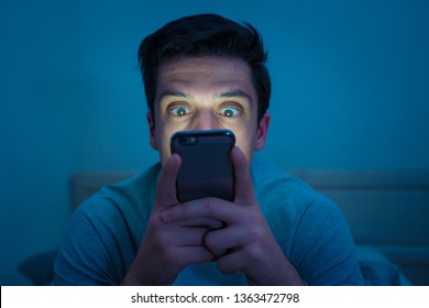 Addicted man chatting and surfing on the Internet with smart phone late at night in bed. Bored, sleepless and tired in dark room with moody light. In insomnia and mobile addiction concept. - Shutterstock ID 1363472798