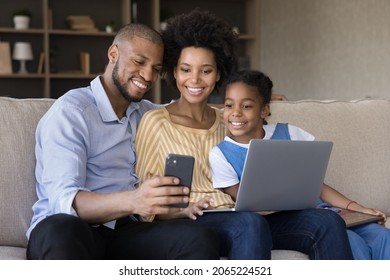 Addicted to modern tech happy bonding african american family parents and small kid daughter posing for photo on cellphone, distracted from using computer application at home, spending time online. - Powered by Shutterstock