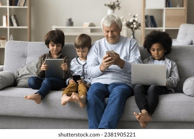 Addicted in modern tech and internet usage multigenerational people spend time at home, great-grandpa and great-grandsons using diverse wireless devices, ignoring each other absorbed in on-line games - Powered by Shutterstock