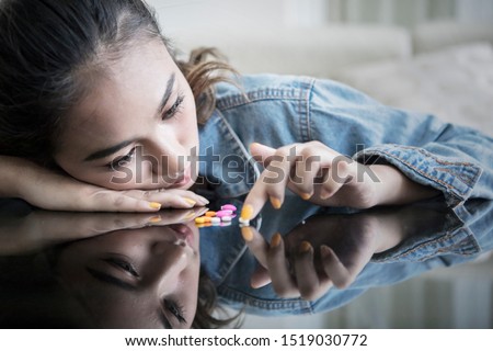 Addicted teenage girl looks depressed while holding drugs on the table at home