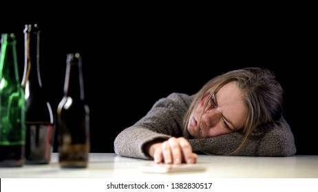 Addicted weak-willed woman lying on table near bottles of alcohol, hopelessness - Shutterstock ID 1382830517
