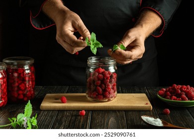 Adding aromatic fresh mint to raspberry drink by hands. Concept of preserving raspberries for long-term storage. - Powered by Shutterstock