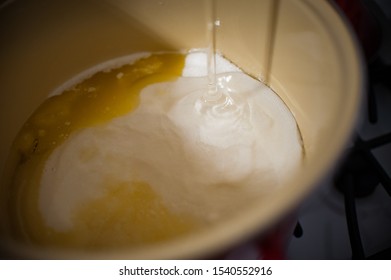 Adding Bottle Of Clear Corn Syrup To Pot Of Sugar And Ingredients On Stove