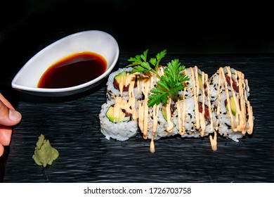 Adding The Finishing Touches To A Portion Of Spicy Tuna California Sushi Rolls Covered With A Spicy Mayo Dressing 