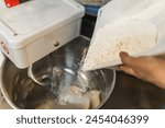 adding flour into the electric mixer machine to knead the dough, kitchen concept. High quality photo